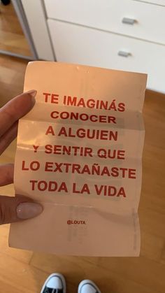 a person holding up a piece of paper with spanish words on it in their left hand