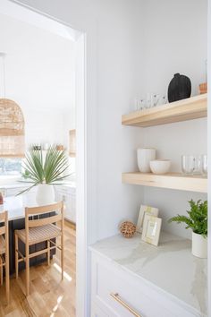 a dining room table and some shelves with plants