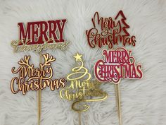 three merry christmas cake toppers sitting on a white furnishing with the words merry christmas written in gold and red