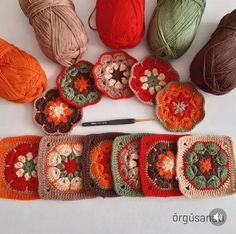 several crocheted grannys and balls of yarn are arranged on a white surface