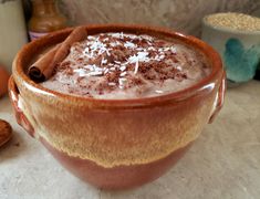 a cup filled with chocolate and cinnamon on top of a counter next to other ingredients