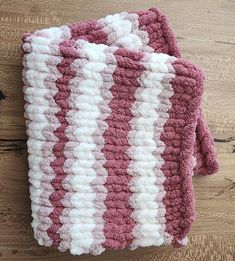 two pink and white crocheted dishcloths sitting on top of a wooden table