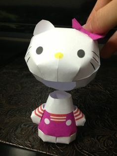 a hand is touching the hello kitty paper doll that has been made into an origami cat