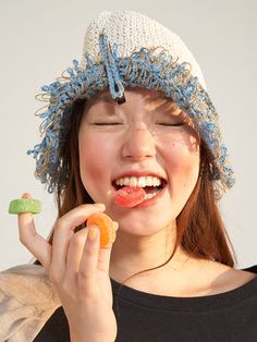 a young woman wearing a knitted hat and holding a candy in one hand and a candie in the other