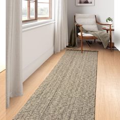 a living room with a chair and rug on the hardwood floor next to a window