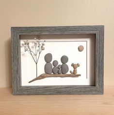 a shadow frame with some rocks and a teddy bear in the middle on a wooden table