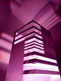 a very tall building with some lights on it's sides in front of a purple background