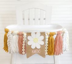 a white chair with a flower on it and some tassels hanging from the back