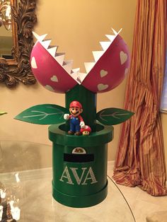 a green box with a pink and white mushroom sitting on it's side in front of a mirror