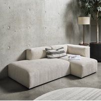 a living room filled with furniture next to a wall mounted planter and potted plants