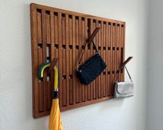 an umbrella, wallet and purse hanging on a wooden peg board mounted to the wall