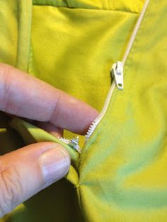 a person is opening the zipper of a green jacket with their thumbnails in