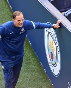 a man in blue is holding onto the wall at a soccer game with his arms outstretched