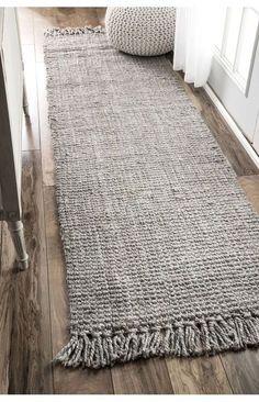 a gray rug with fringes on the floor