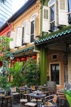 an outdoor cafe with tables and chairs in front of the building that has many windows