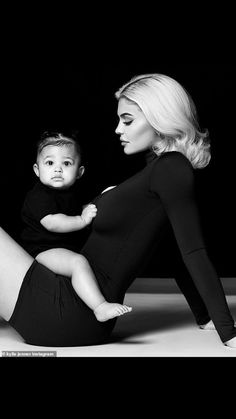 a woman is holding a baby in her lap and posing for a black and white photo