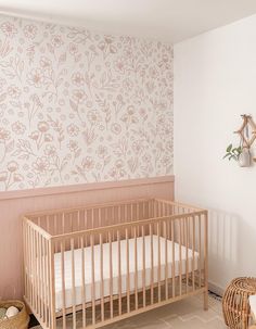 a baby's crib in the corner of a room with pink wallpaper