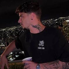 a man with tattoos on his face and neck standing in front of a cityscape