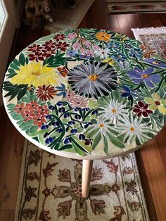 a table with flowers painted on it in a room next to a rug and door