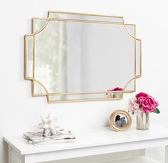 a white table topped with a mirror and vase filled with pink flowers on top of it