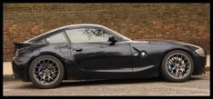 a black sports car parked in front of a brick wall