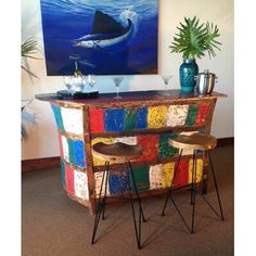 a colorful bar with two stools next to it and a painting on the wall