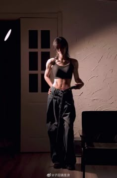 a woman is standing in the dark with her hands on her hips