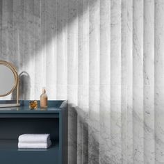 a bathroom with marble walls and flooring, including a blue vanity table next to a mirror