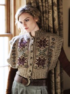 a woman standing in front of a window wearing a sweater and pants with flowers on it