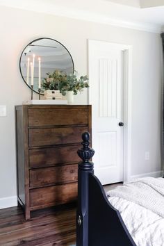 a bedroom with a bed, dresser and mirror on the wall in front of it