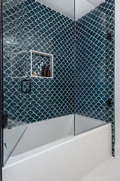 a bathroom with a glass shower door and blue tiles on the wall, along with white flooring