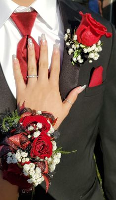 a person wearing a suit and tie with red roses on their lapel flower bouquet