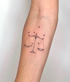 a woman's arm with a tattoo on it that shows the scale of justice