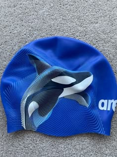 an orca whale swims in the water on top of a blue swimming cap