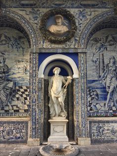 a statue in front of a blue and white wall