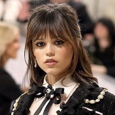 a woman with long hair wearing a black and white shirt, bow tie and jacket