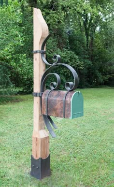 a mailbox attached to a wooden post in the grass with trees in the background