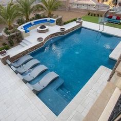 an outdoor swimming pool with lounge chairs next to it