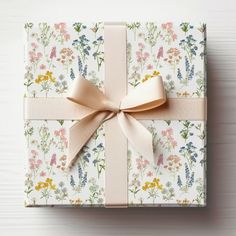 a gift wrapped in floral paper with a gold bow