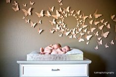 a baby in a crib is surrounded by many butterflies that are flying over the wall