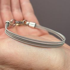 a hand holding a silver bracelet on top of it