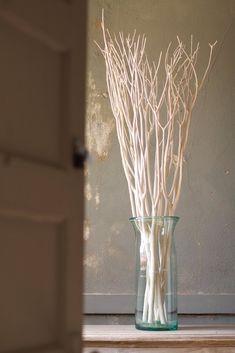 a vase filled with branches on top of a wooden table