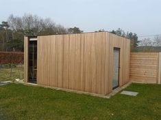 a wooden building sitting on top of a lush green field