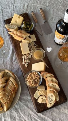 a table topped with bread and cheese next to wine glasses