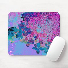 a computer mouse sitting on top of a desk next to a pink and blue mouse pad