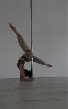 a man is doing a handstand on the floor in front of a pole