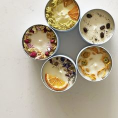 four bowls filled with different types of food on top of a white countertop next to an orange slice