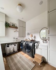 a washer and dryer in a small room with white cabinets, wood flooring