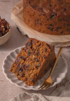 a piece of cake sitting on top of a white plate next to a bowl of nuts