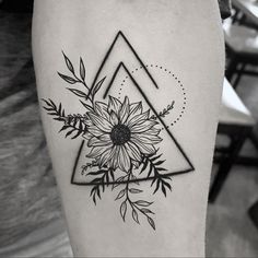 a black and white photo of a sunflower tattoo on the right thigh, with triangles in the background